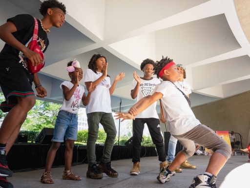 A group of students dance outside of a museum
