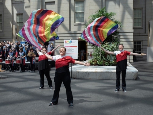 Group of three people in matching outfits wearing rainbow Pride flags.
