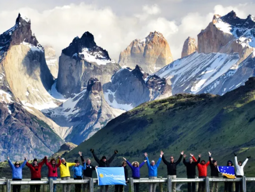 A group of travelers stand in front of a mountain landscape.
