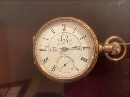 Small handheld watch with gold rim, roman numerals, and slim hands.