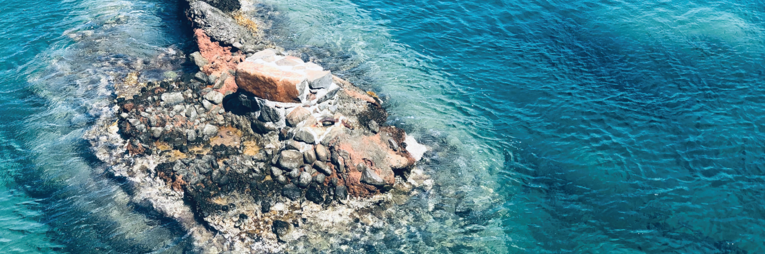 Aerial view of rocks in the blue ocean.